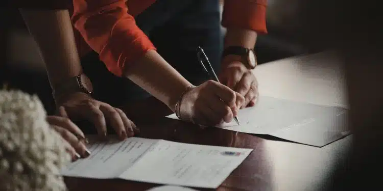 person in orange long sleeve shirt writing on white paper