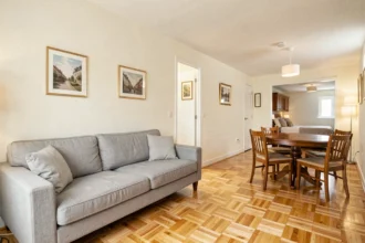 Vue grand angle du séjour et de la salle à manger d'un appartement T3 avec parquet clair et mobilier moderne