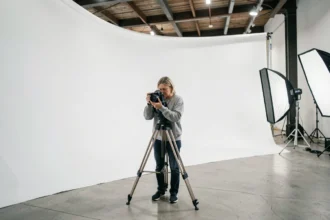 Studio photo professionnel avec cyclorama blanc à La Roche sur Yon, photographe ajustant son appareil sur trépied